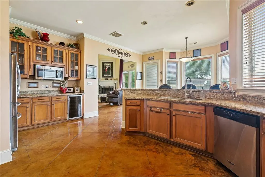 A kitchen with wood cabinets, granite countertops, stainless steel appliances, and a view into the living room.