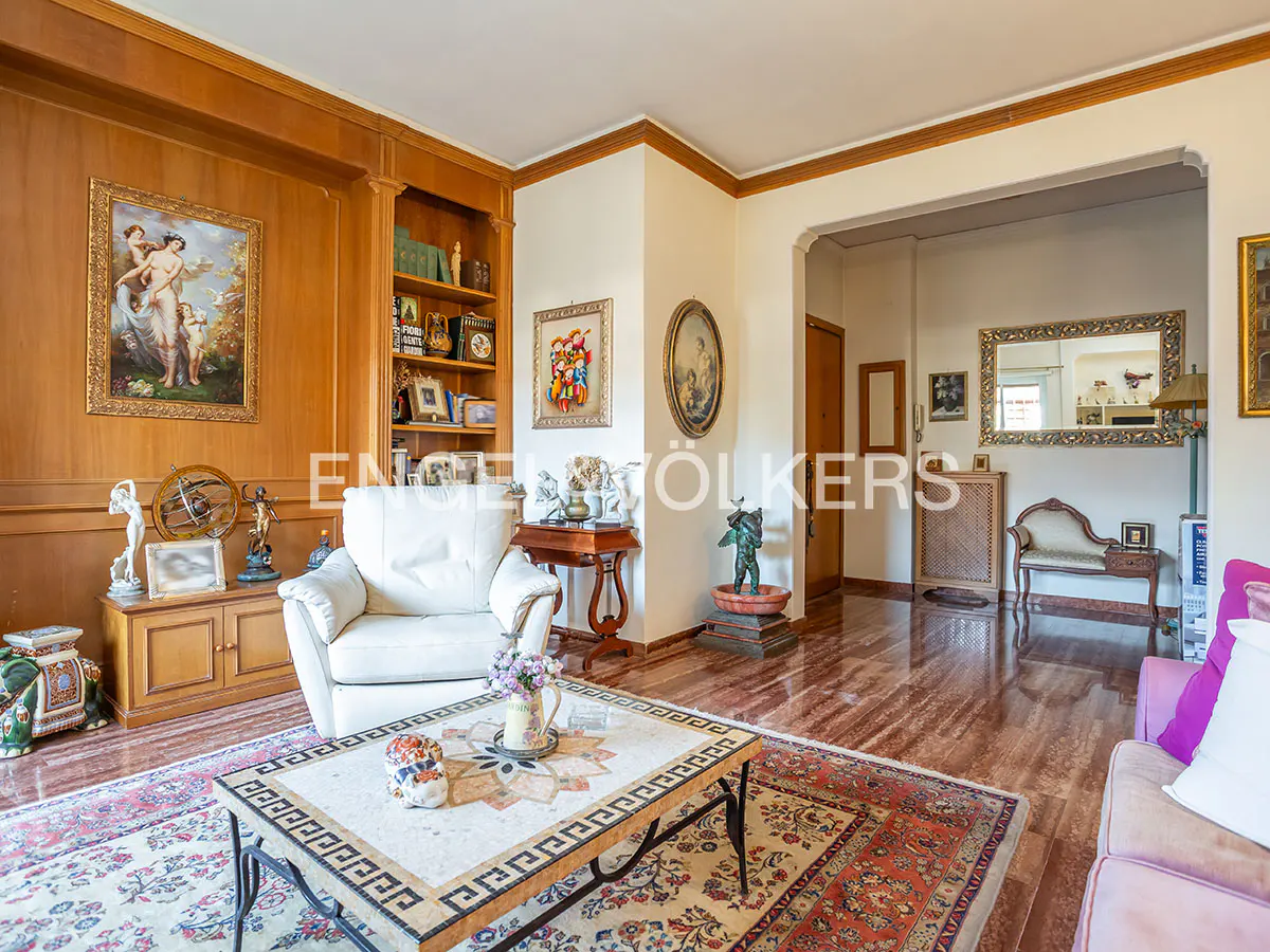 A living room with wood paneling, a white armchair, and a mosaic coffee table on a patterned rug.