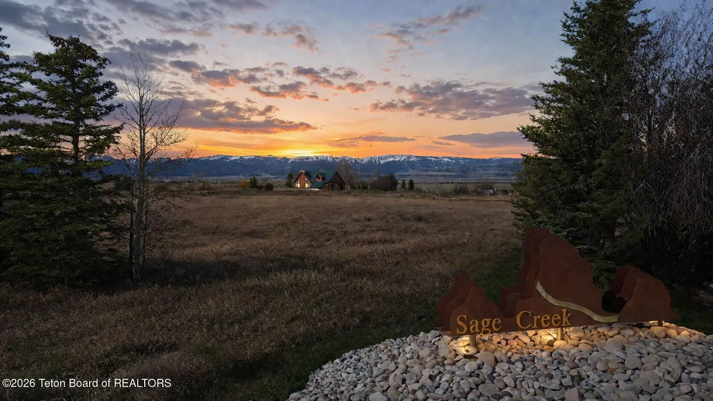 Scenic view of Sage Creek property at sunset. Mountains in the distance, sign in foreground.