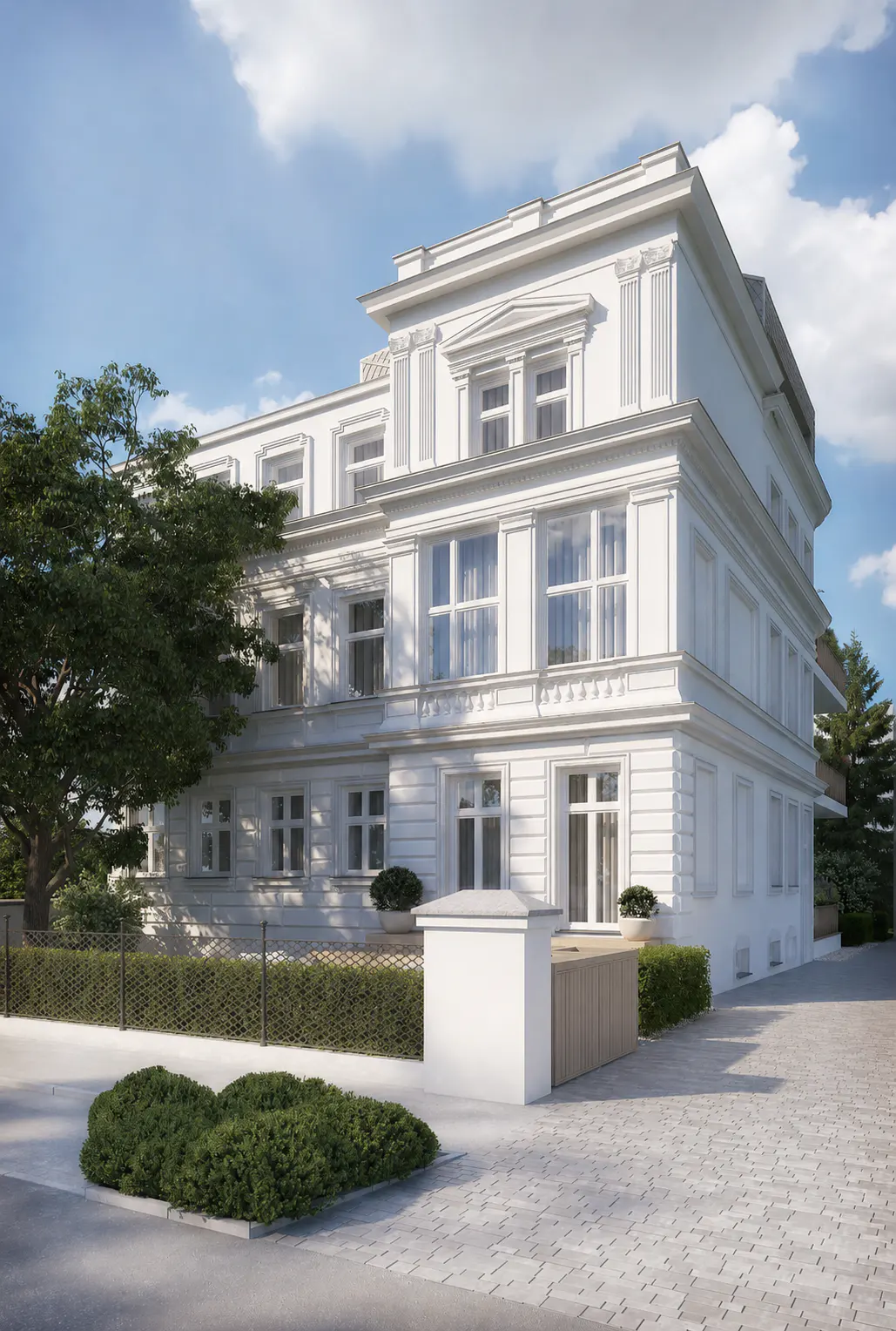 A white, multi-story neoclassical building with large windows, surrounded by manicured hedges and a paved driveway.