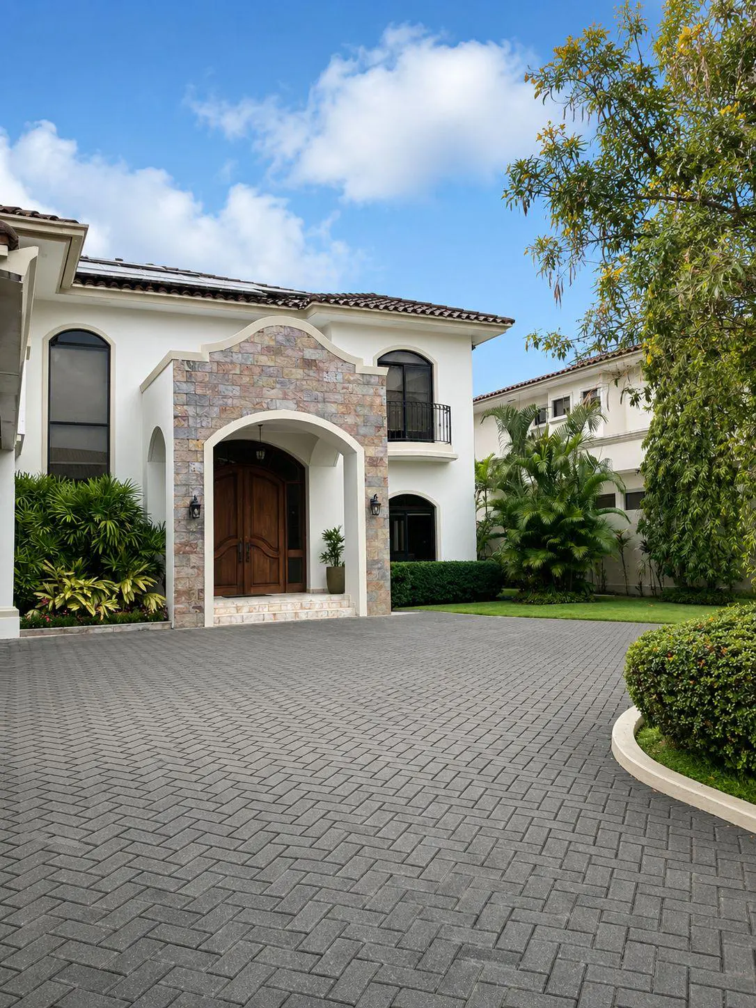 Exterior of a two-story white house with a stone archway and a gray brick driveway.