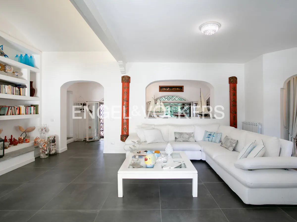 Bright living room with white sectional sofa, square coffee table, built-in bookshelves, and red decorative pillars.