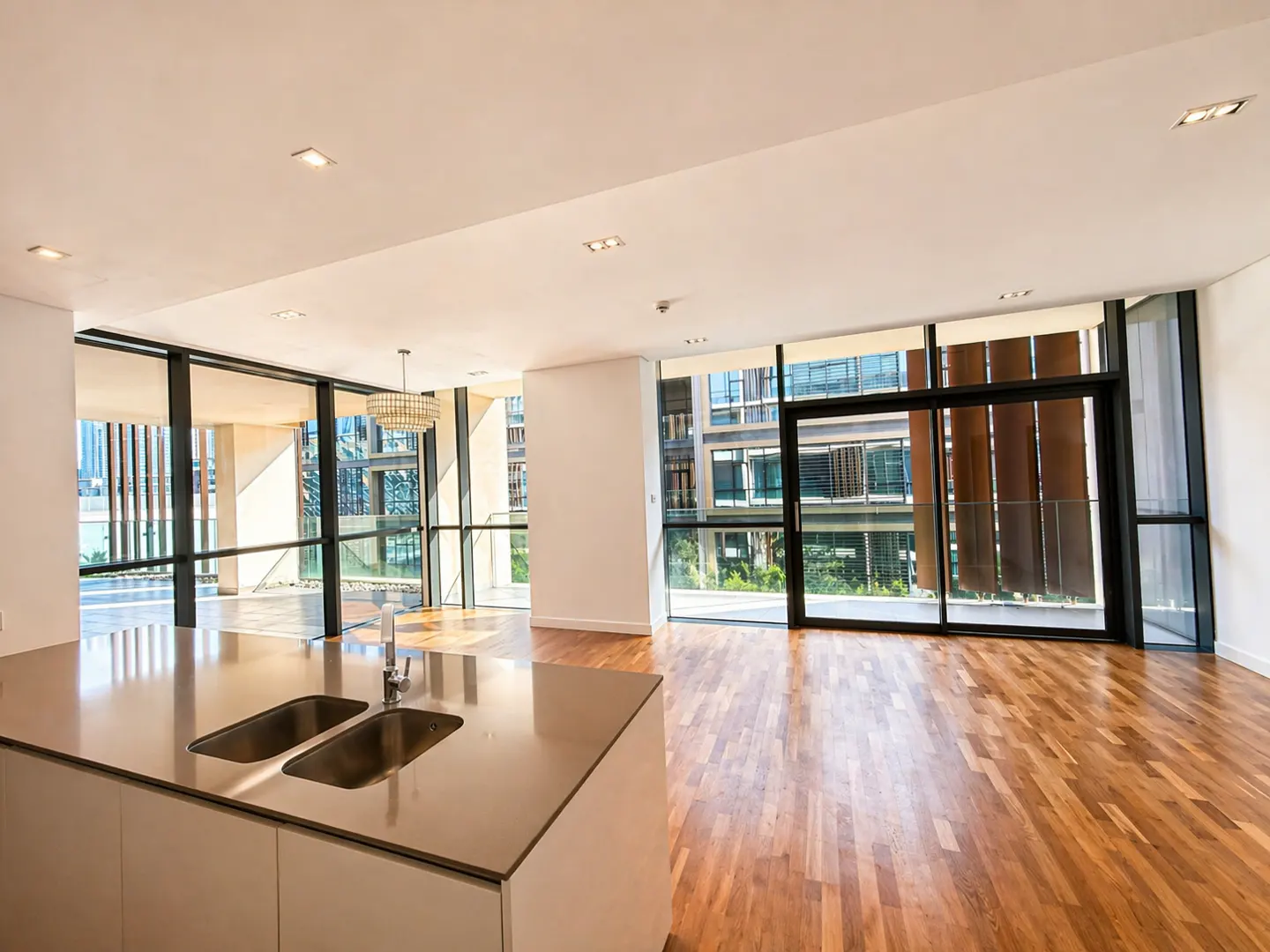 Bright, modern apartment interior with wood floors, large windows, and a kitchen island with a double sink.