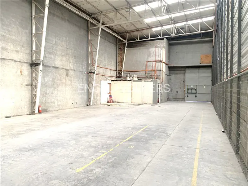 An empty warehouse with concrete floors, walls, and metal support beams.