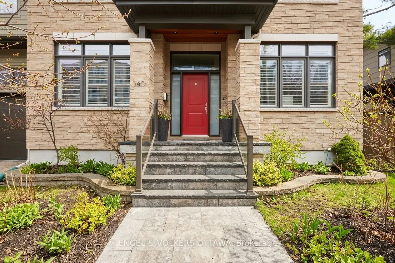 Exterior view of a stone house with a bright red front door and stone steps with metal railings.