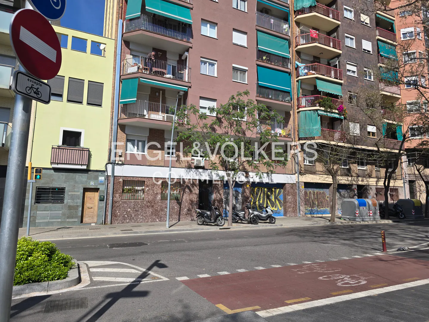 Street view of multi-story buildings with balconies and green awnings. Engel & Volkers logo is visible. A bike lane is in the foreground.