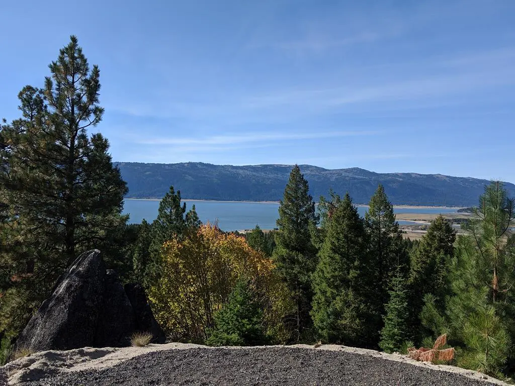 Scenic view of a lake surrounded by mountains and trees under a blue sky.