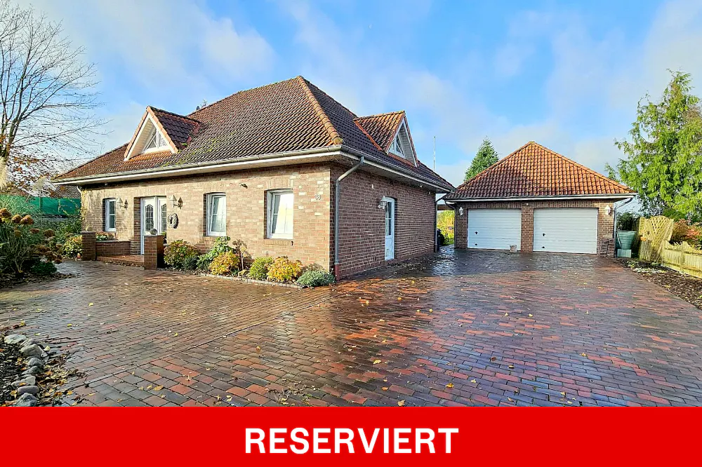 Exterior view of a brick house with a red tile roof and a detached two-car garage on a brick driveway.
