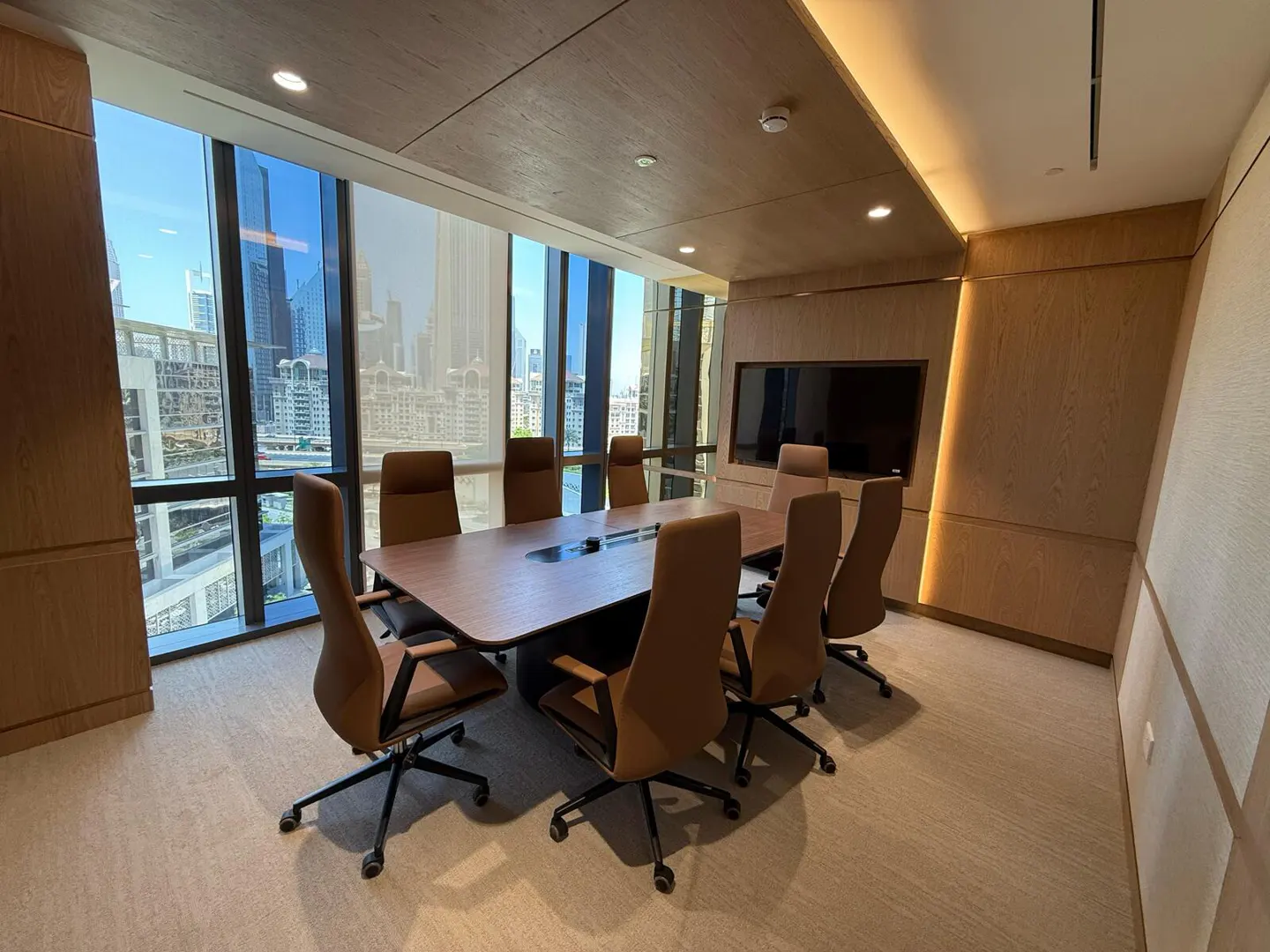 Conference room with a wood table, brown leather chairs, and a large window with a city view.