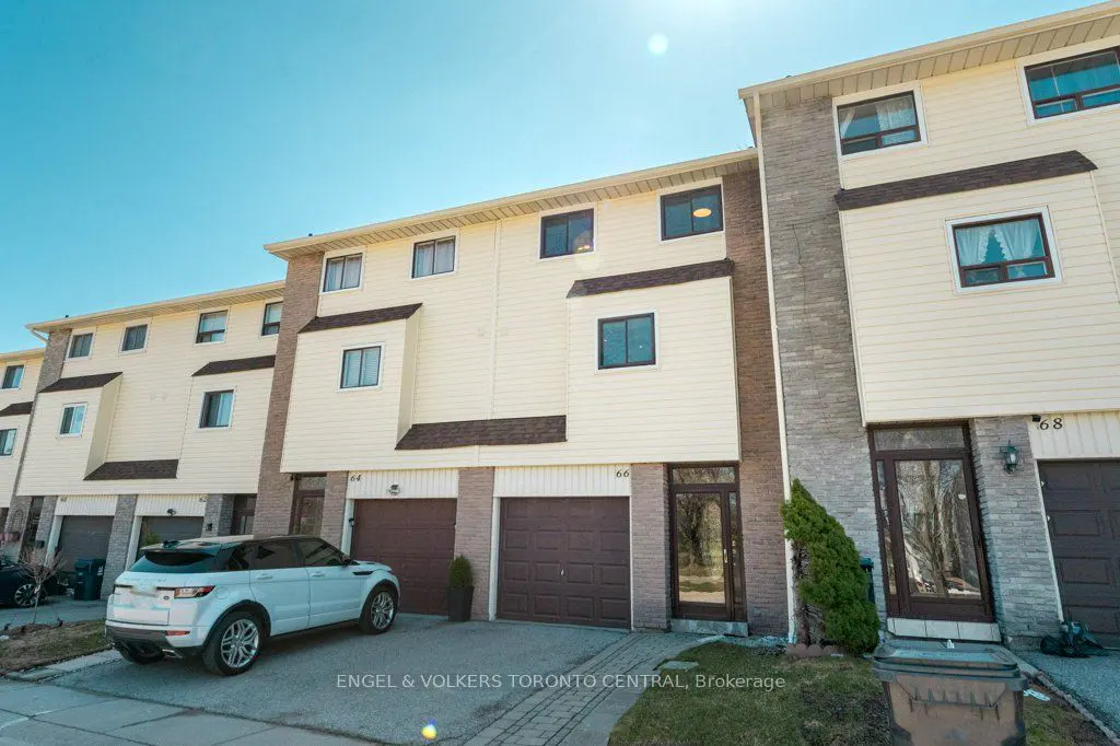 Row of townhouses with beige siding and brick accents under a blue sky. A white Range Rover is parked in front.