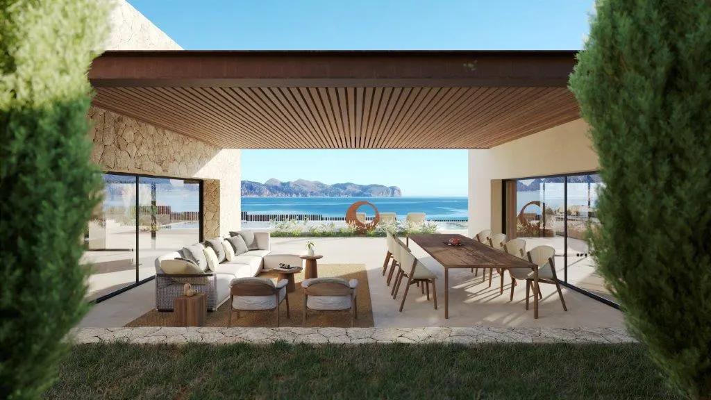 Outdoor patio with a white sectional sofa, chairs, and a long wooden table with chairs overlooking the ocean.