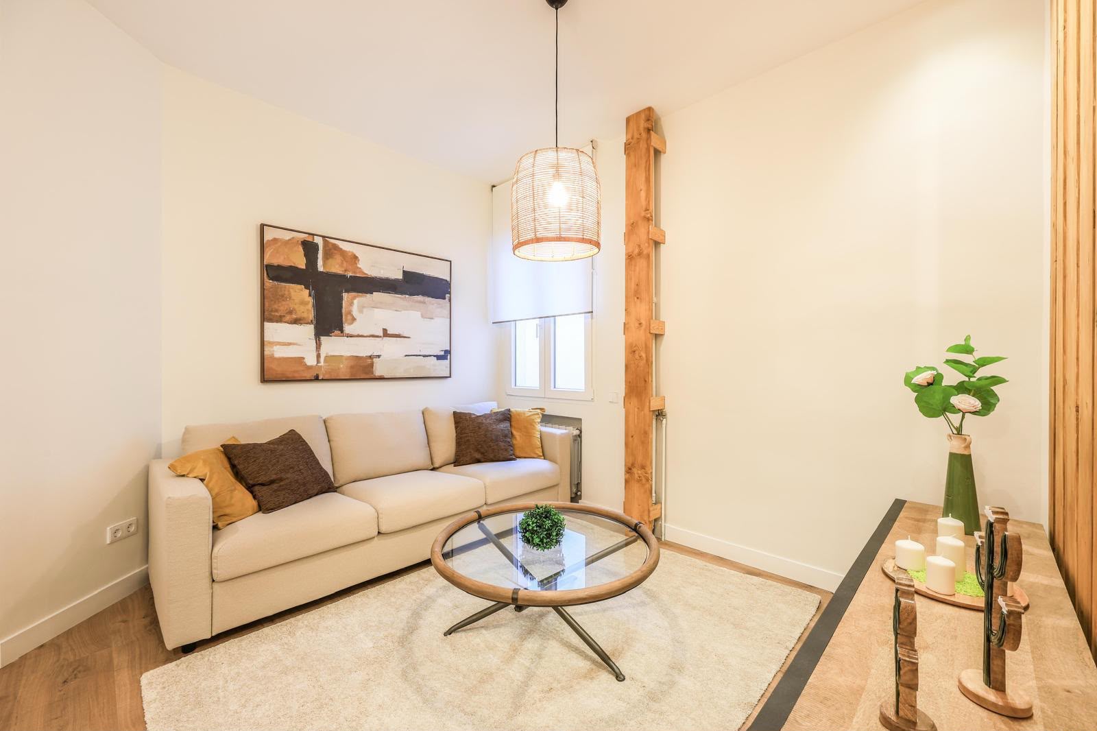 Modern living room with a beige sofa, glass coffee table, abstract wall art, and a wooden pillar feature. [AI-generated text]
