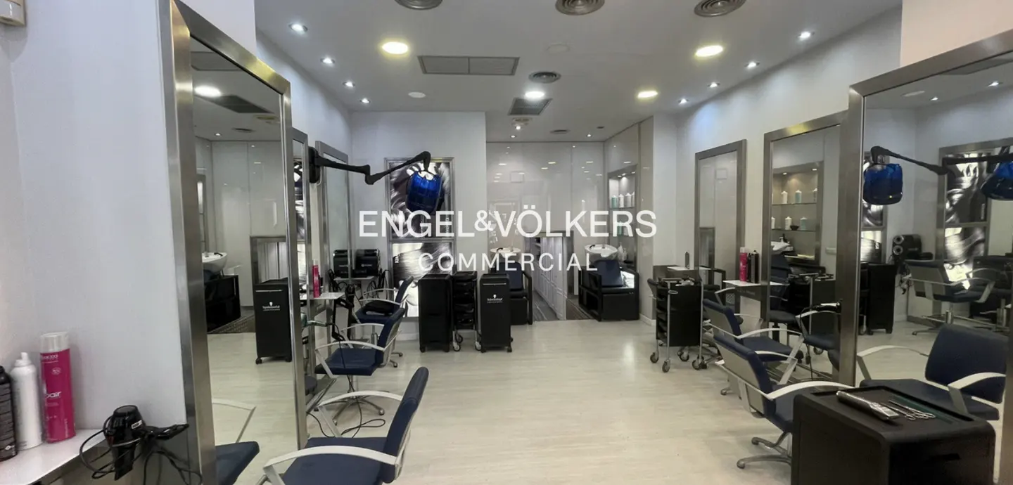 Bright, modern salon with blue chairs, large mirrors, and black equipment. Engel & Völkers Commercial logo visible on a glass wall.