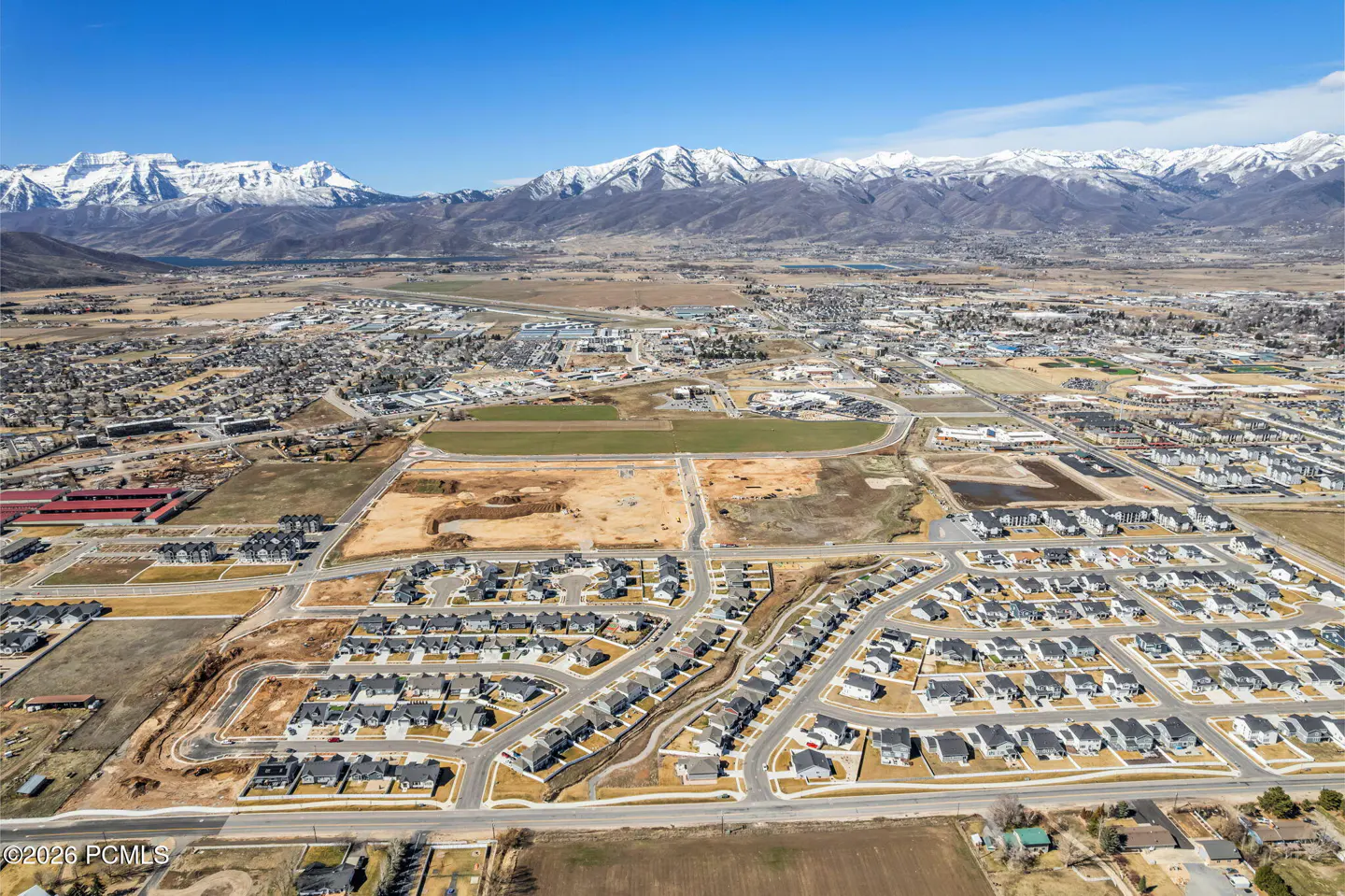 Aerial view of a suburban neighborhood with snow-capped mountains in the background under a clear blue sky.