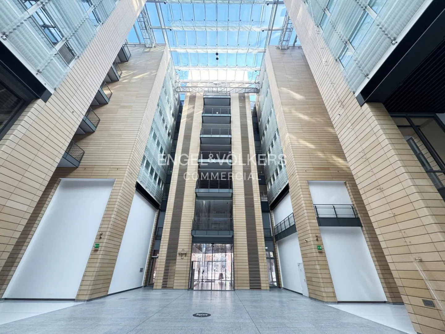 Interior view of a commercial building with a glass ceiling and the Engel & Volkers logo.