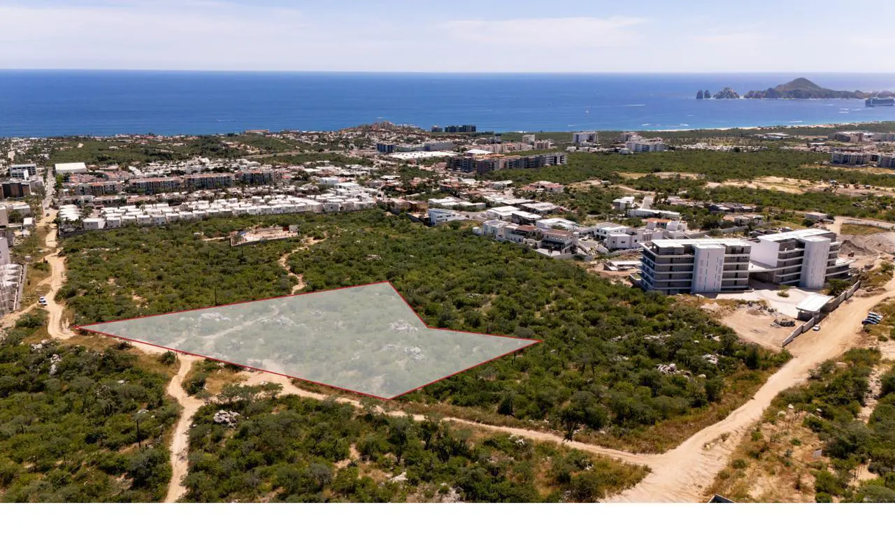 Aerial view of a vacant lot outlined in red, with ocean and city views in the background.