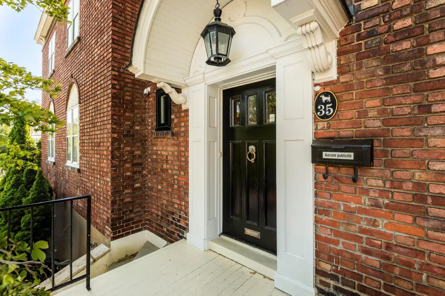 Brick house exterior with a black door framed in white, a hanging lantern, and a mailbox. The house number "35" is displayed.