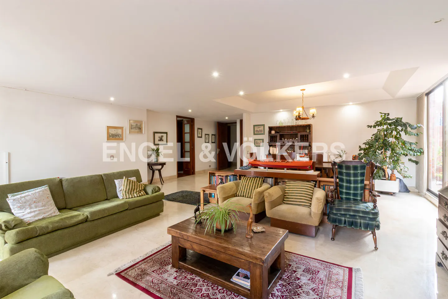 A living room with a green sofa, two armchairs, a wooden coffee table, and a dining table with chairs.