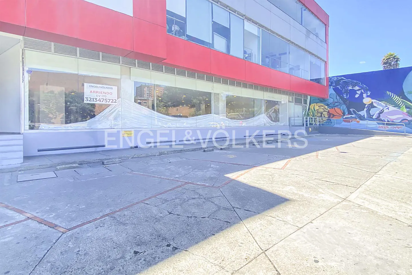 Exterior of a red and white building with Engel & Volkers signage. A mural is visible on the right side of the building.