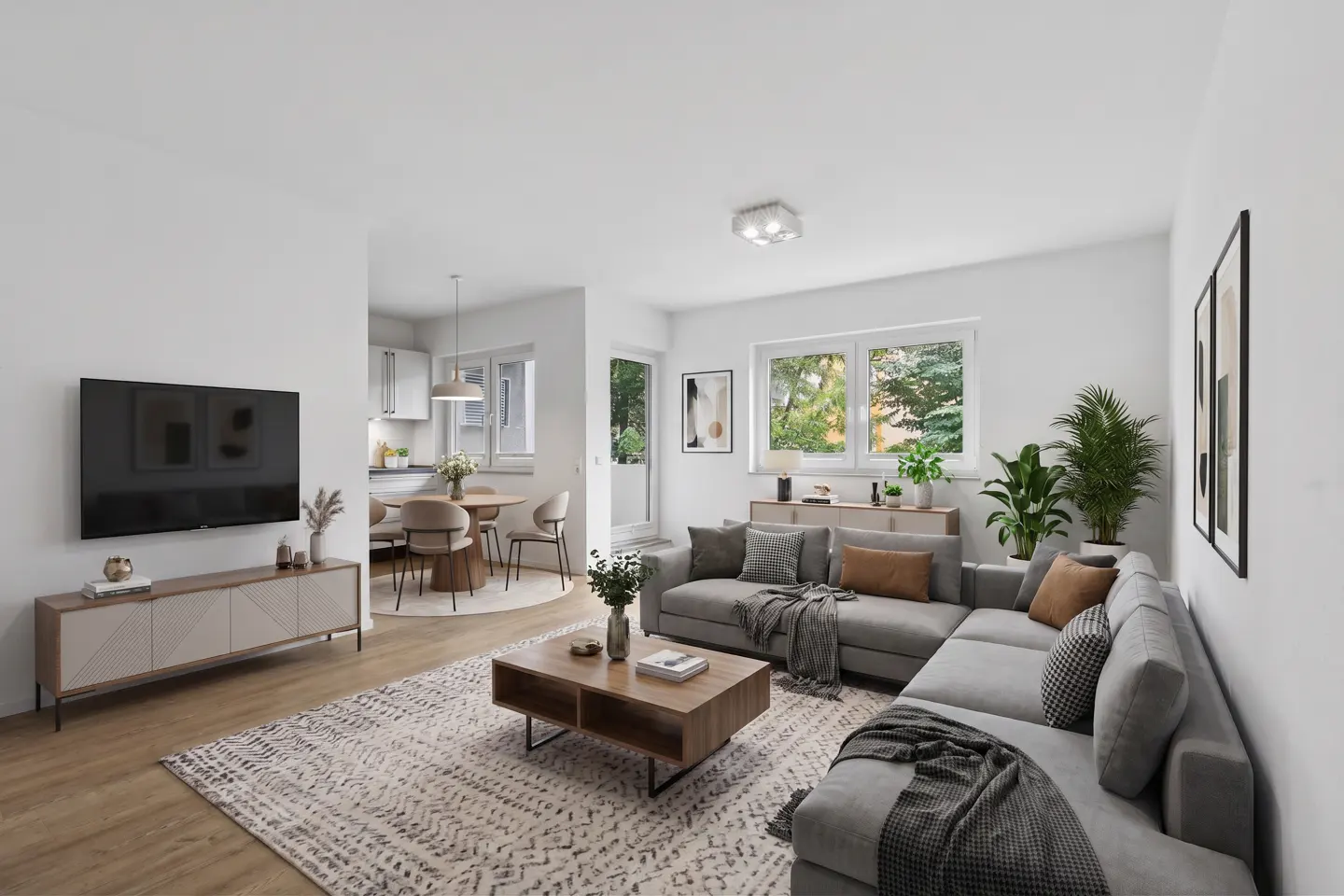 Modern open-plan living room with a grey sectional sofa, wooden coffee table, TV, and dining area with light wood floors.
