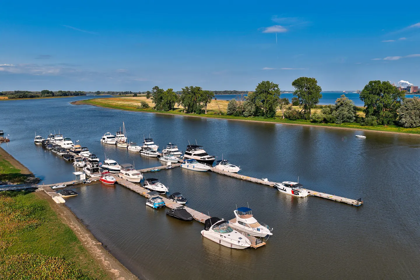 Aerial view of a marina with boats docked on a river under a blue sky.