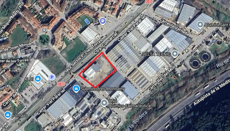 Aerial view of an industrial area with a red outline highlighting a vacant rectangular plot of land near major roads.
