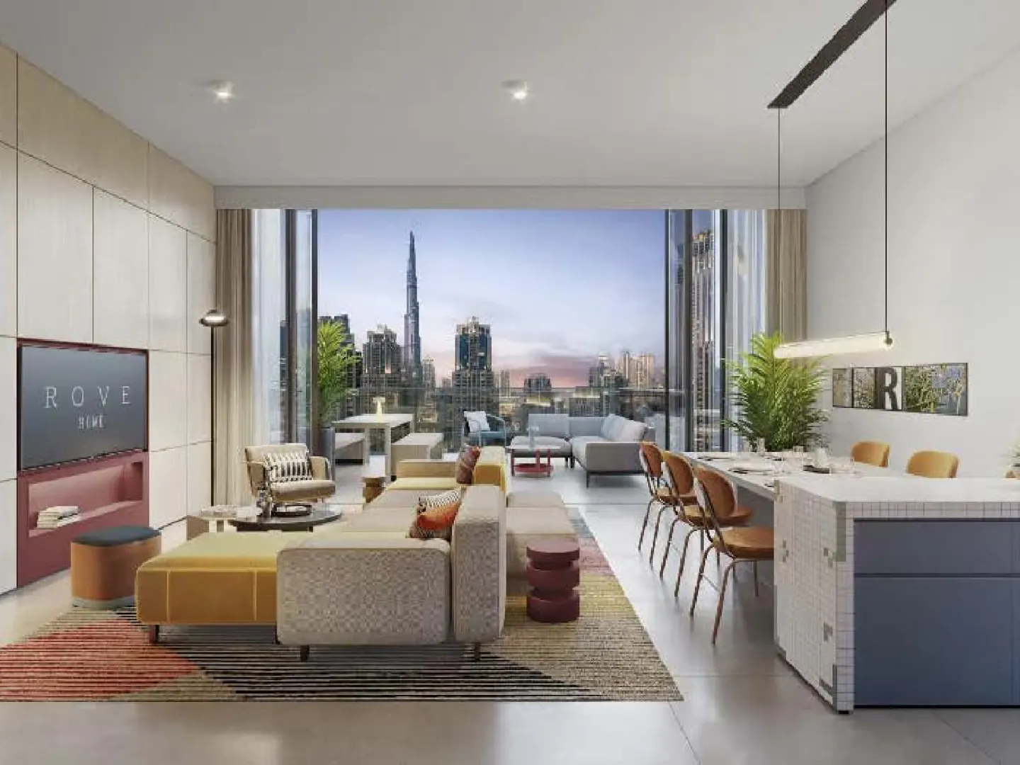 Bright, modern apartment interior with a view of the Dubai skyline. Beige sofa, dining table with chairs, and a TV are visible.