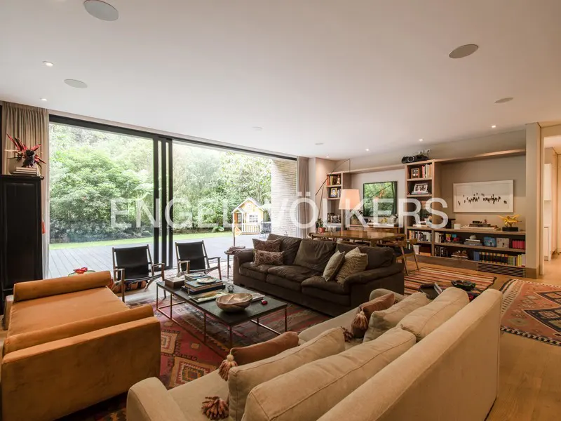A spacious living room with sofas, chairs, and a large window overlooking a green yard.