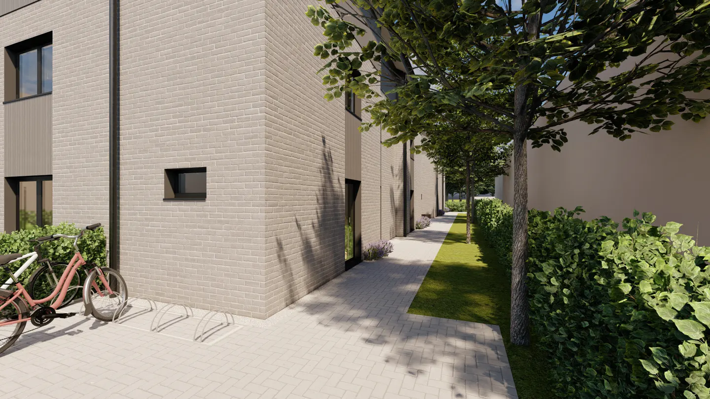 Exterior view of a light brick apartment building with bikes parked in front and a tree-lined walkway.