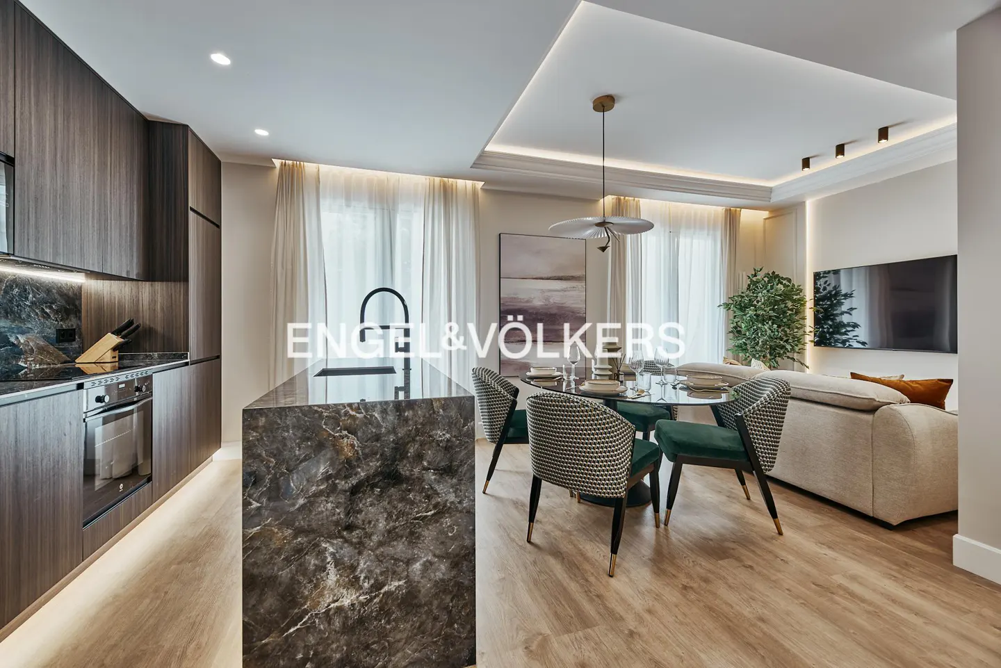 A modern apartment interior with a kitchen island, dining table, and living room. The kitchen features dark wood cabinets and marble countertops.