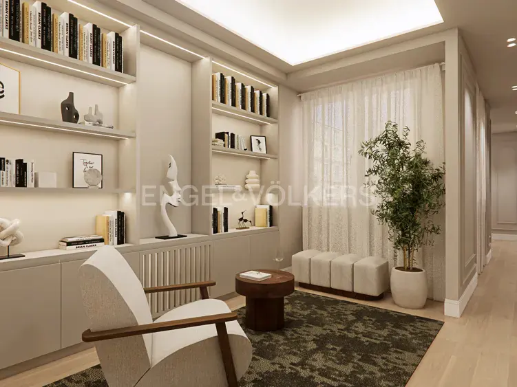 Modern home library with built-in shelves, a white armchair, a small round table, and a potted plant by a window.