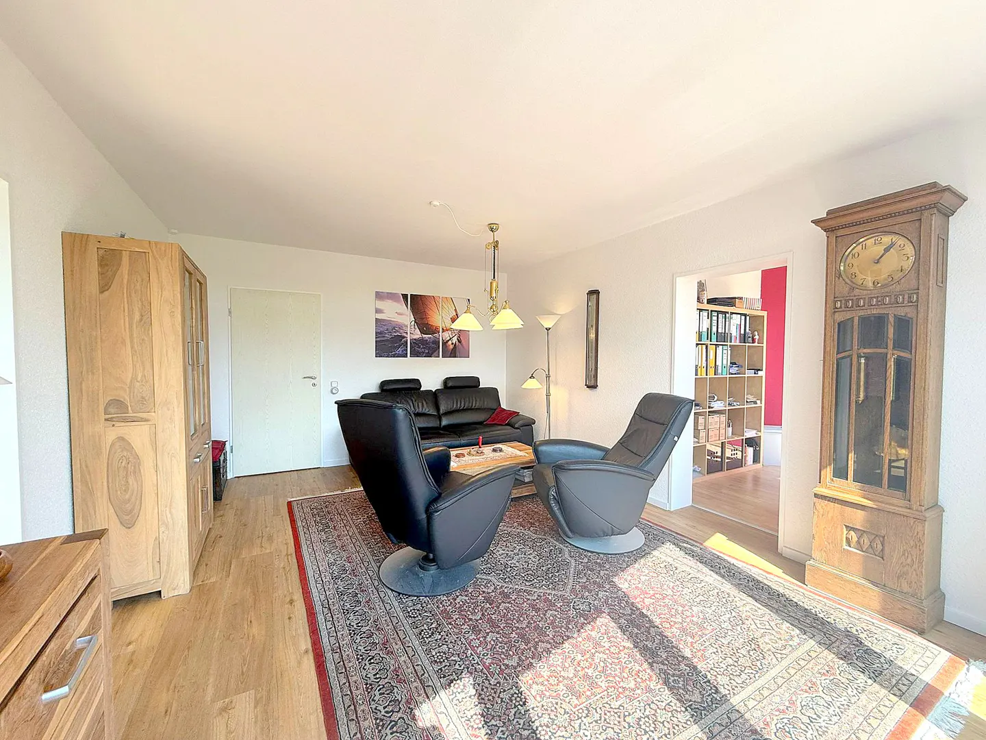 Living room with black leather recliners, sofa, and a wooden grandfather clock on a patterned rug.