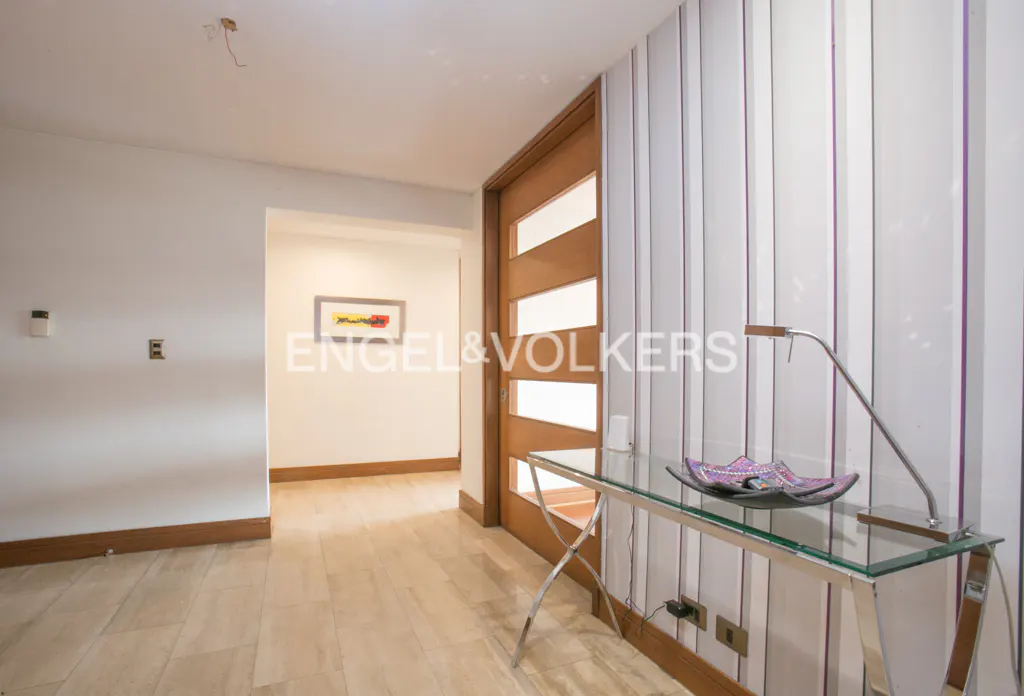 Entryway with a light wood door, striped wallpaper, and a glass table with a lamp and decorative bowl.