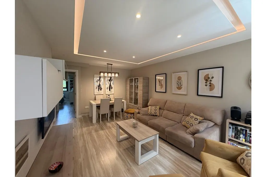 A living and dining area with beige walls, a sofa, a table, and framed art.
