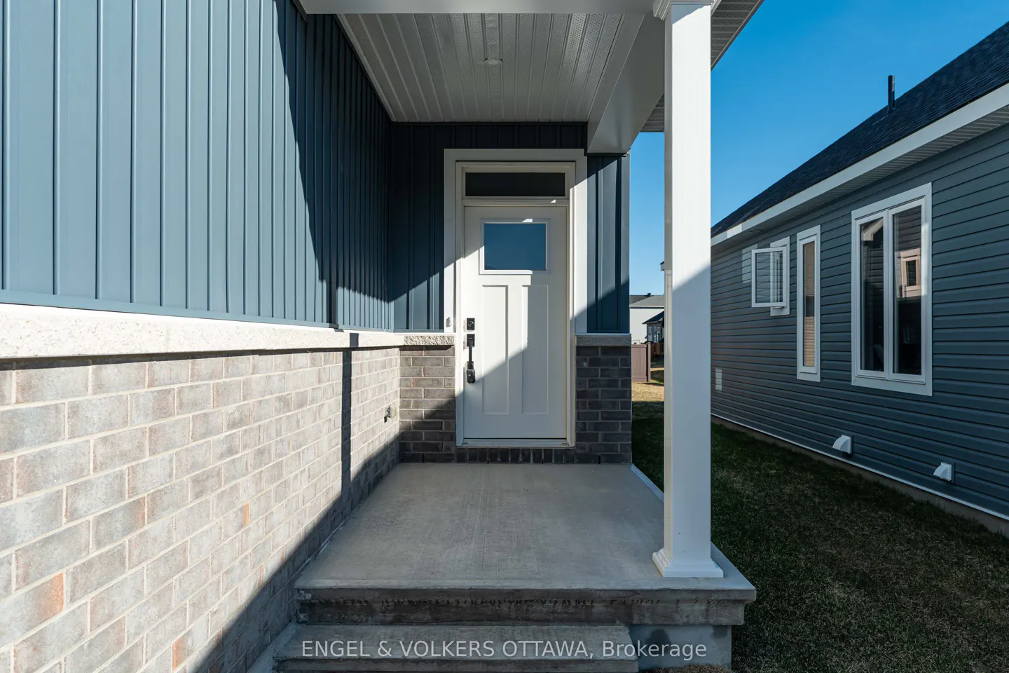 Exterior view of a home's front porch with a white door, blue siding, and brick accents.