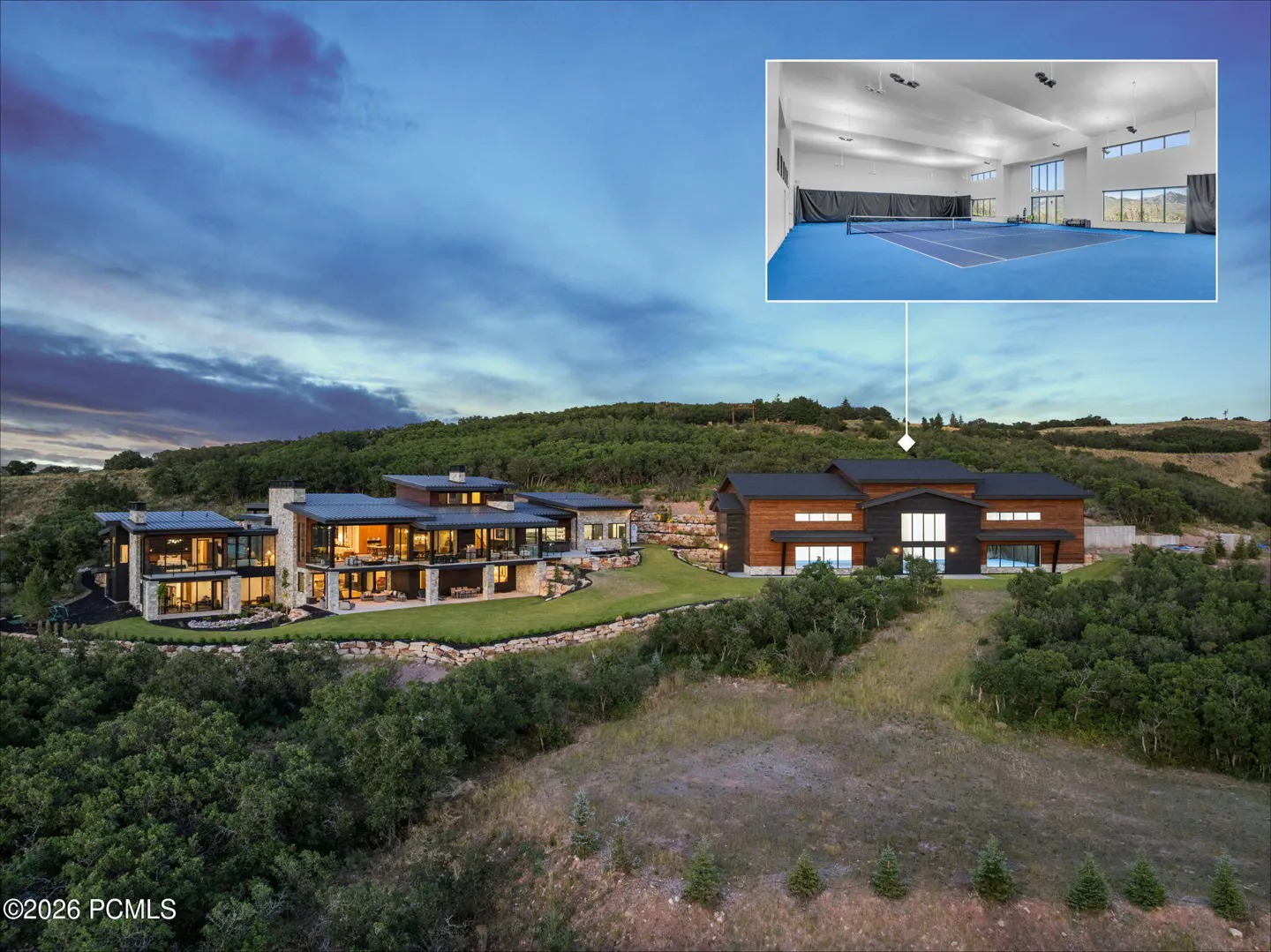 Aerial view of a modern mountain estate at dusk with an inset photo showing an indoor blue tennis court.