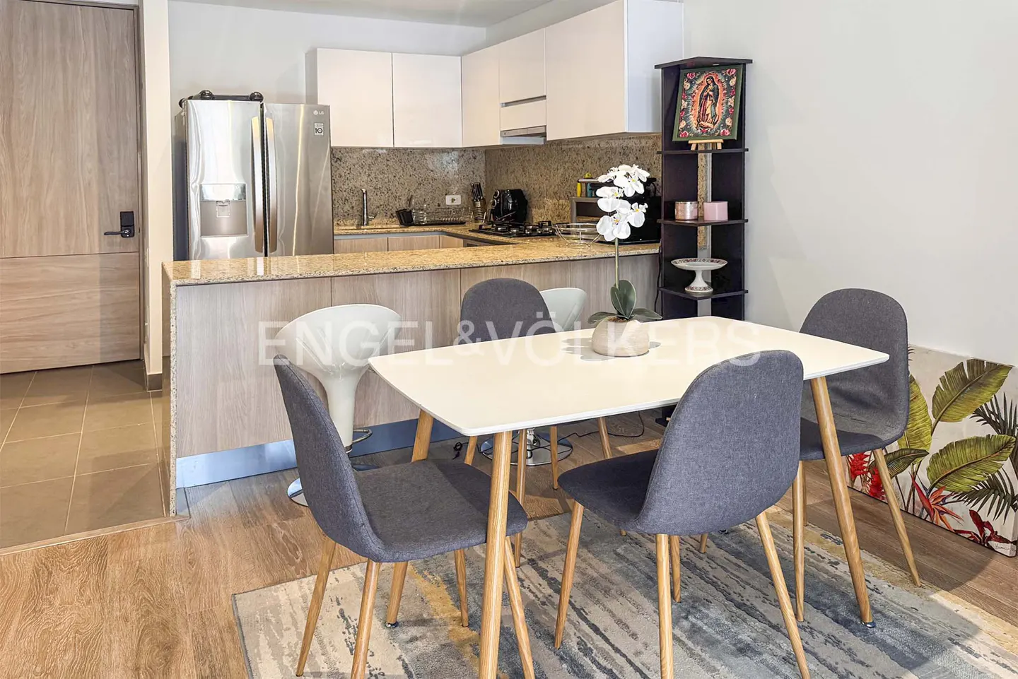 Modern kitchen with white cabinets, granite counters, and a dining area featuring a white table and four grey chairs.
