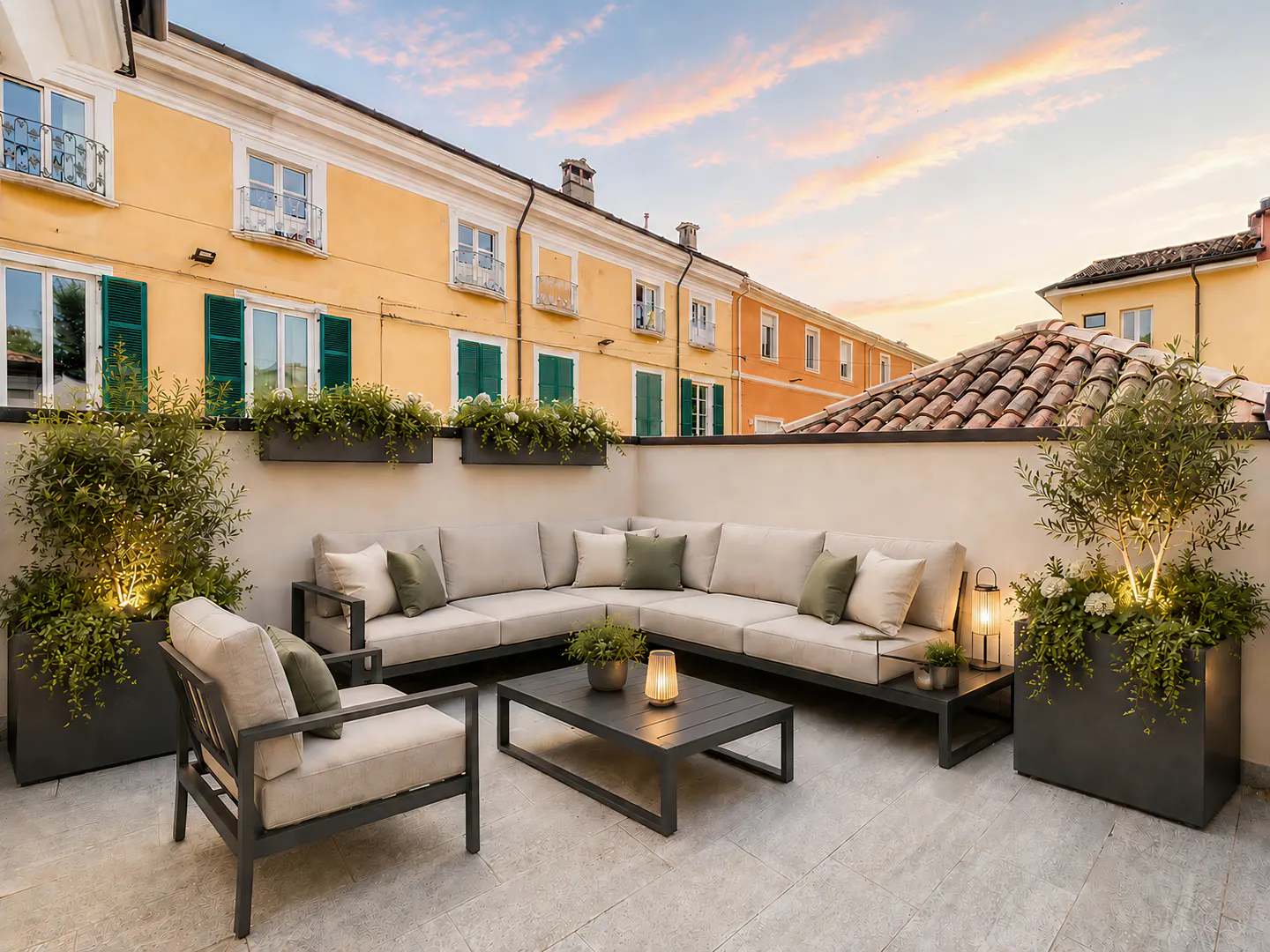 Modern rooftop terrace with beige sectional seating, a coffee table, and potted plants against a yellow building at sunset.
