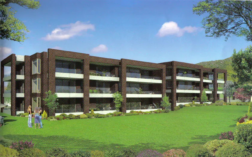 Three-story brown brick apartment building with white balconies and a green lawn. Three people stand on the lawn.
