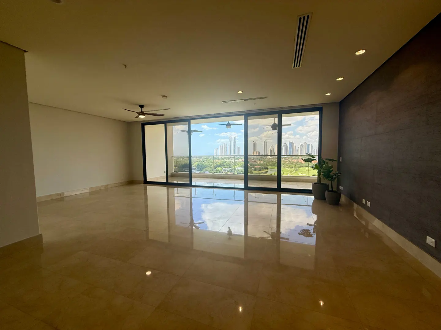 Unfurnished living room with beige tile floors, ceiling fans, and a large sliding glass door with a city view.