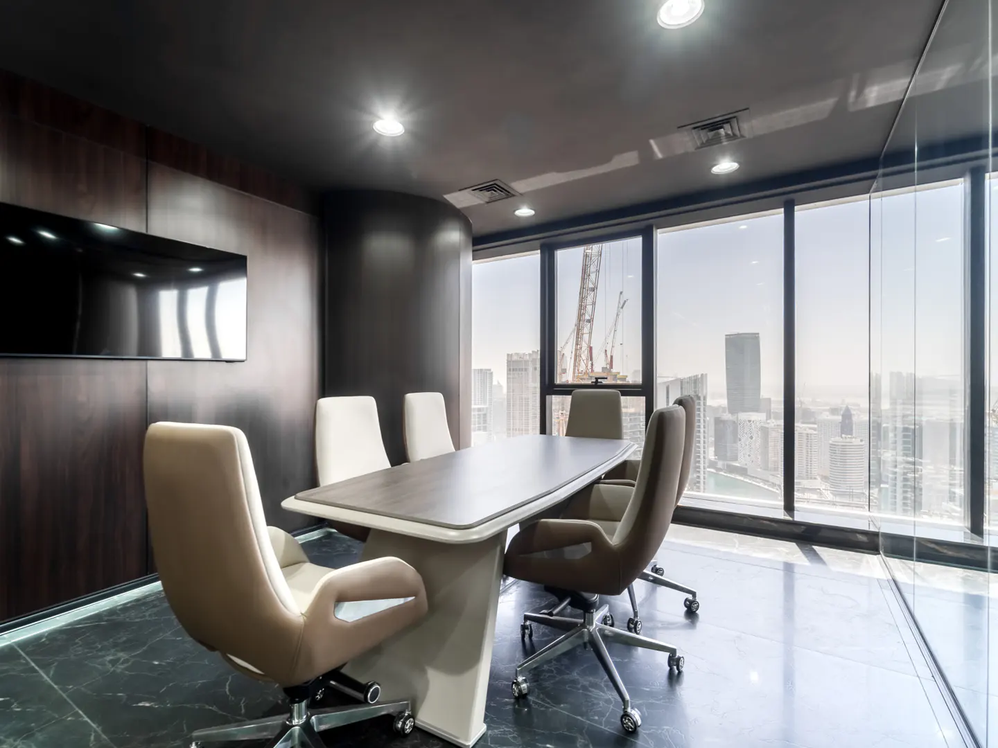 Conference room with a large table, rolling chairs, and a wall of windows overlooking a city skyline.