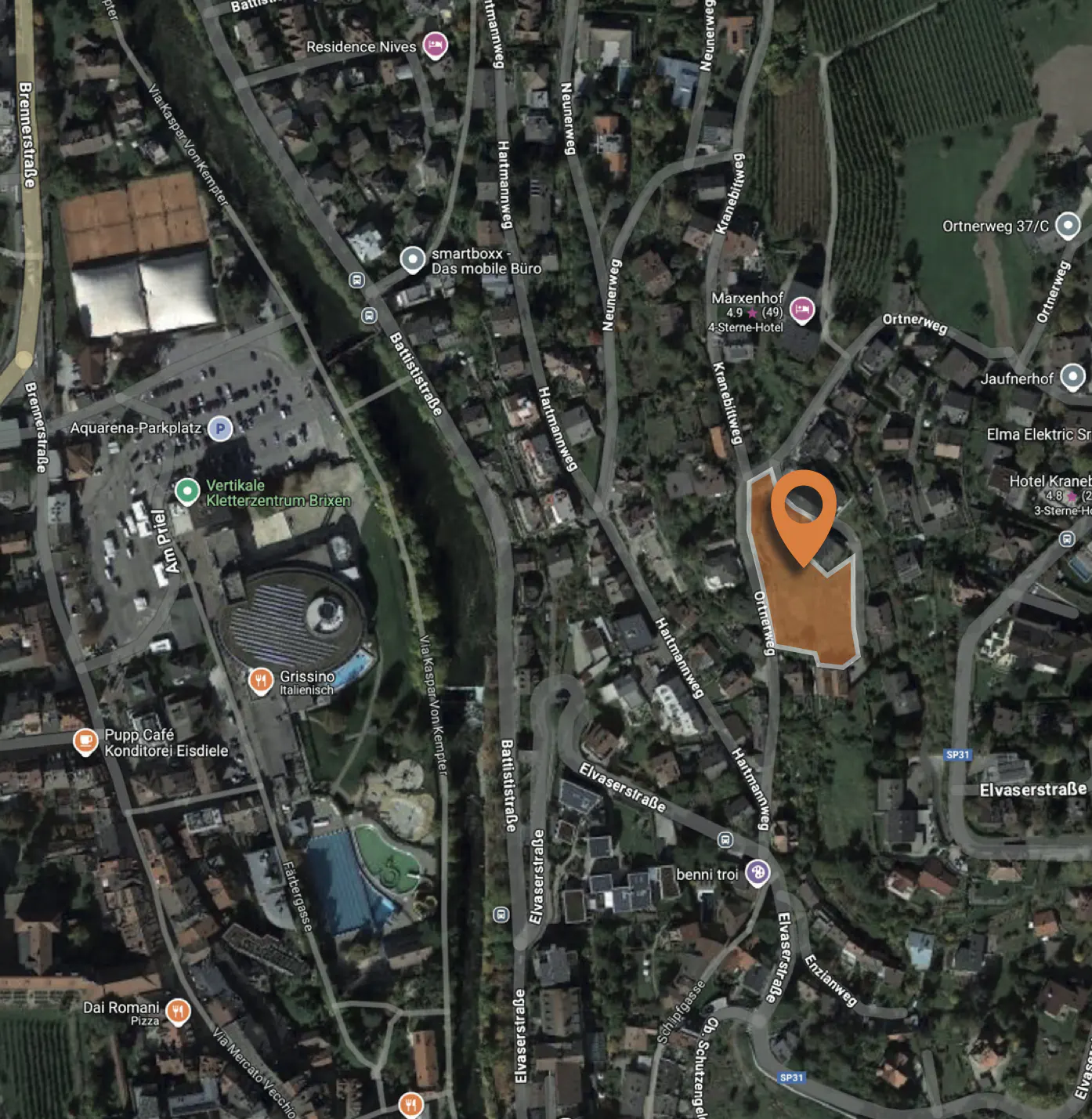 Aerial view of a property in Brixen, Italy, marked with an orange pin, surrounded by streets, buildings, and green spaces.
