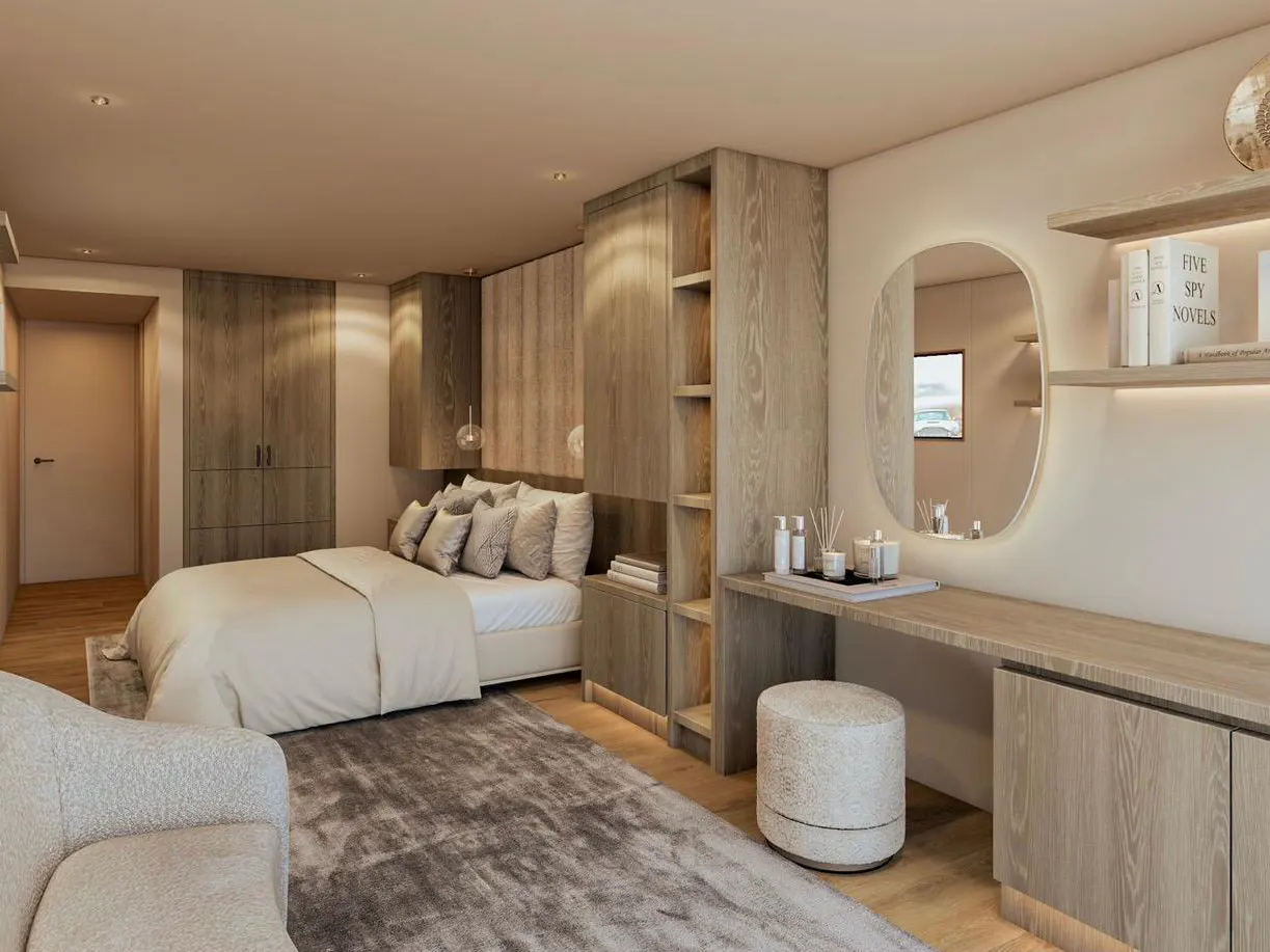 Bedroom with a bed, a vanity with a mirror, and a gray rug. The walls are light beige and the furniture is light wood.