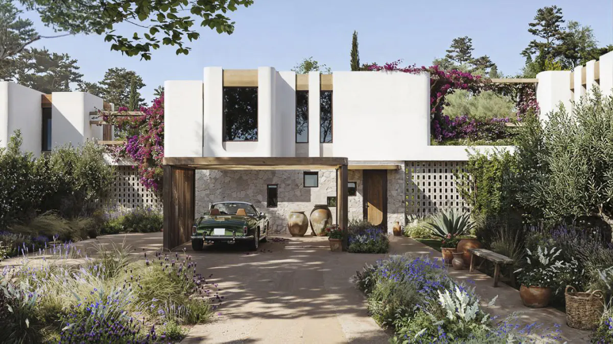Modern white house with a stone carport, a green convertible car, and lush landscaping with purple flowers.