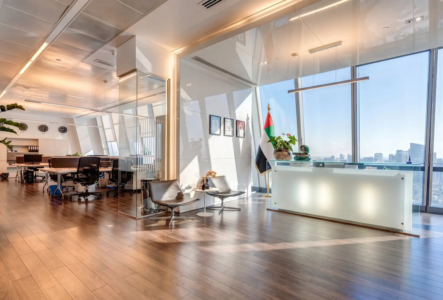 Bright, modern office space with wood floors, glass walls, and a reception desk by a large window with a city view.