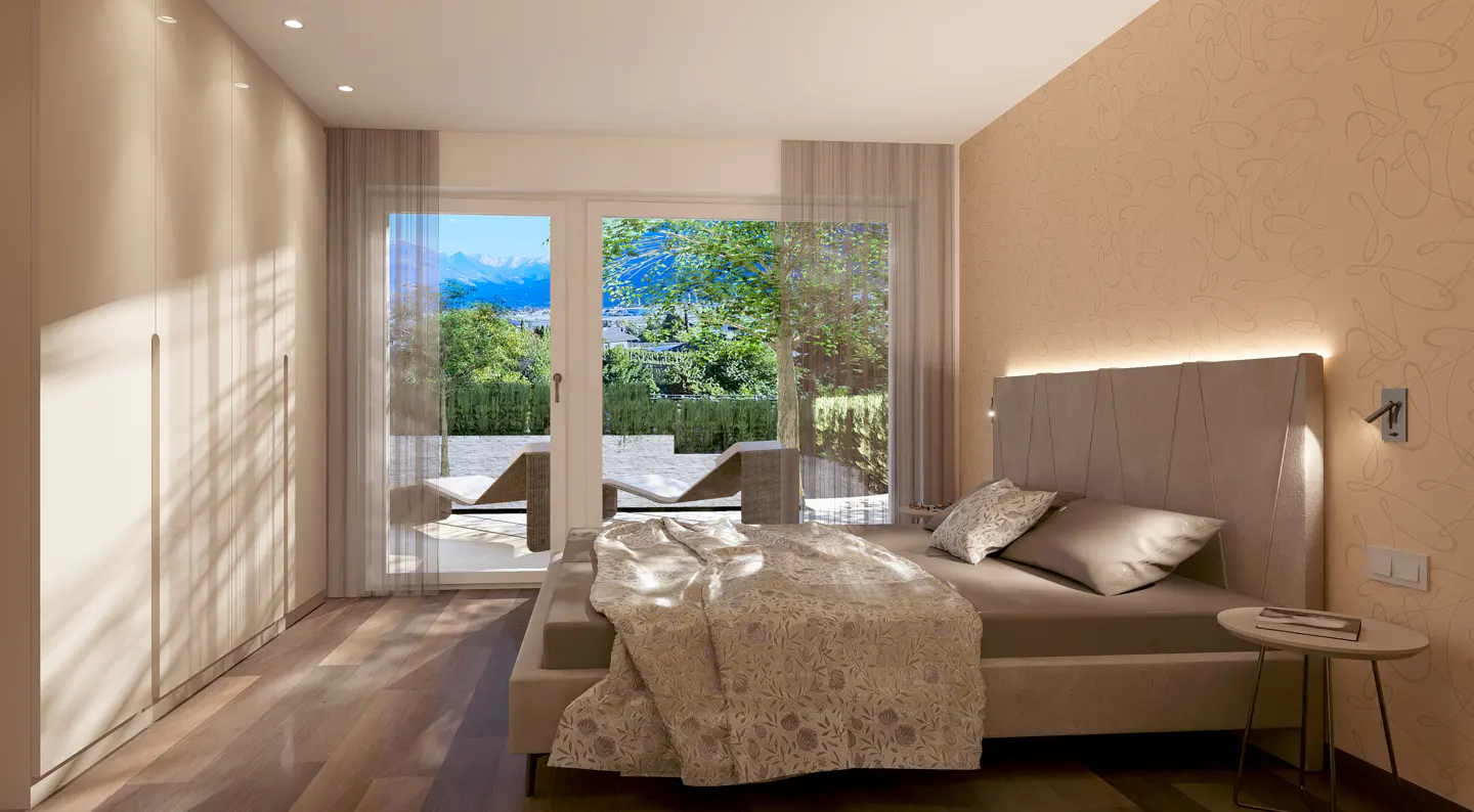 Bedroom with a gray bed, beige walls, and a view of a garden through a glass door. A beige blanket is draped over the bed.