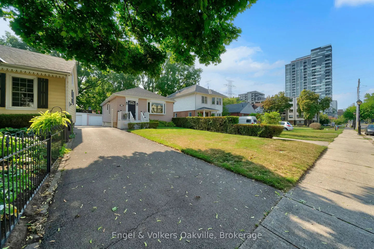 Street view of houses with a tall building in the background on a sunny day.