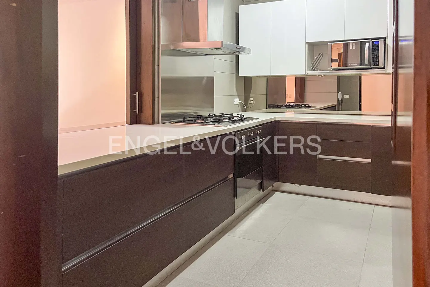 A modern kitchen with white cabinets, brown lower cabinets, stainless steel appliances, and light gray tile flooring.