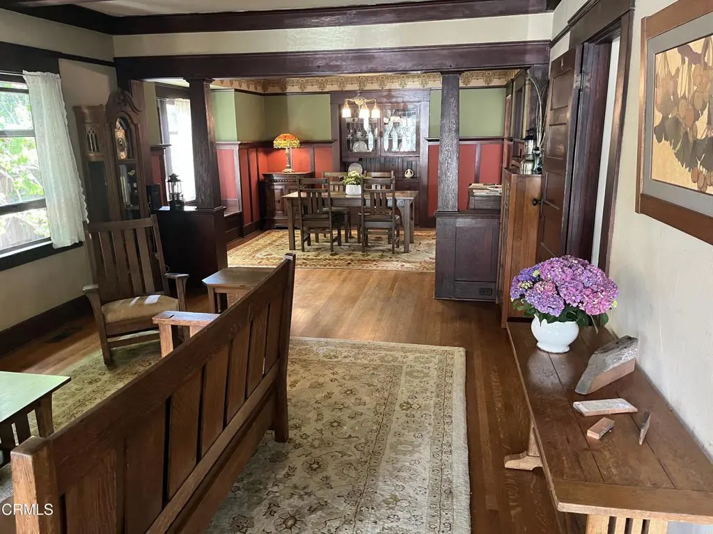 A craftsman-style home interior with wood furniture, hardwood floors, and a dining area visible through an archway.