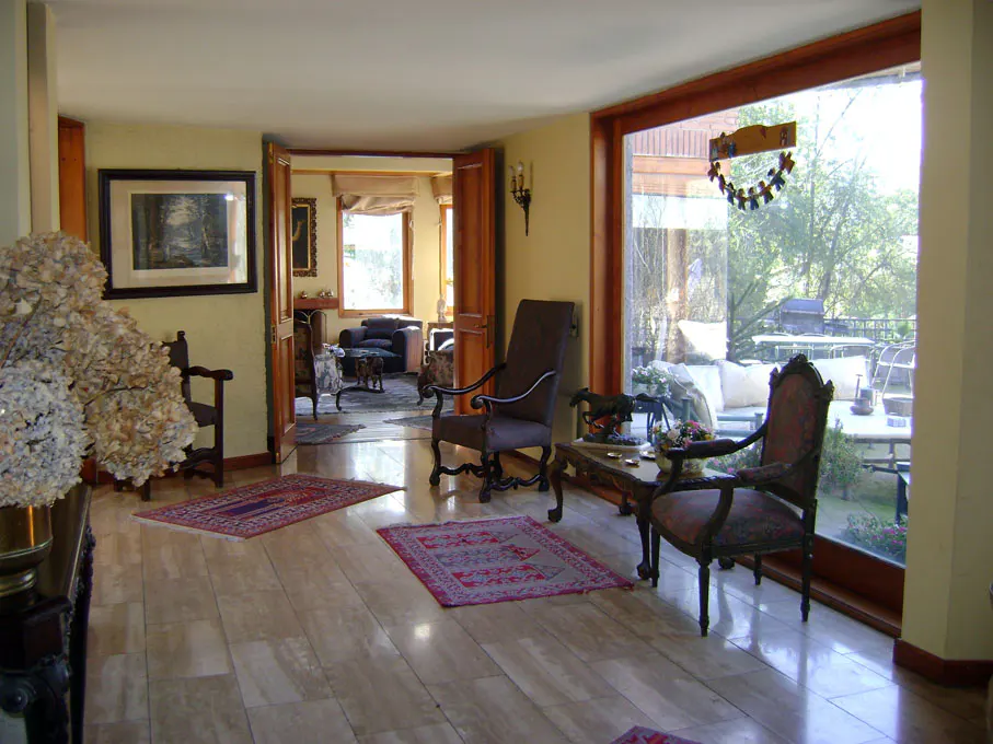 A living room with marble floors, two chairs, and a large window with a view of the outside.